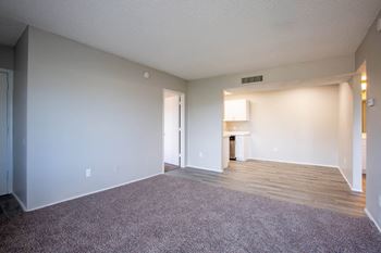 an empty living room with a kitchen in the background at The Vintage Apartments, Tucson, SC